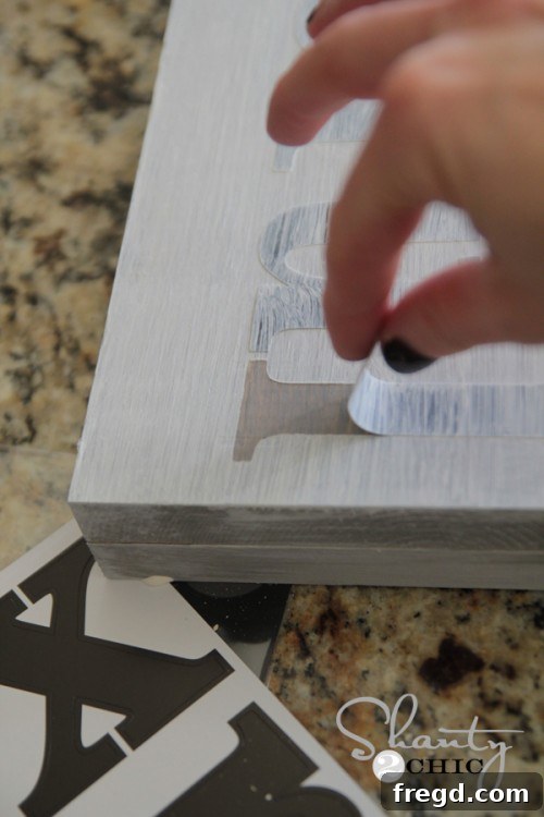 Carefully peeling off stencil letters to reveal painted word on sign