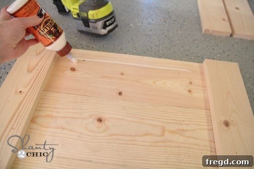 Applying wood glue to the top and bottom ends of the sign for frame attachment