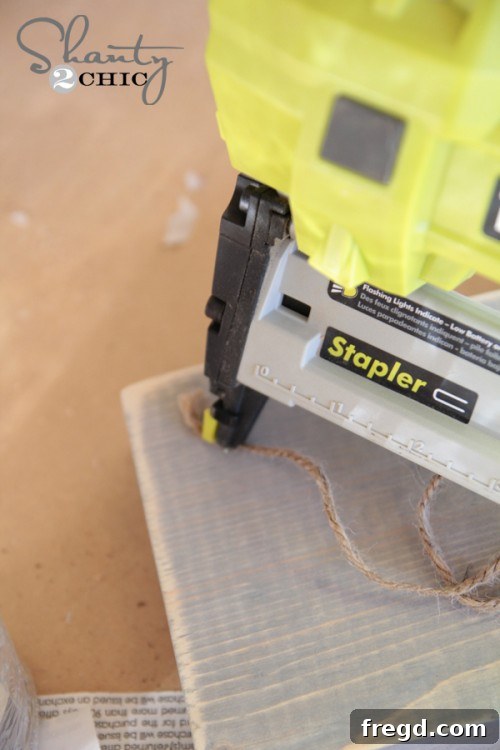 Using a staple gun to attach jute twine to the wood block frame