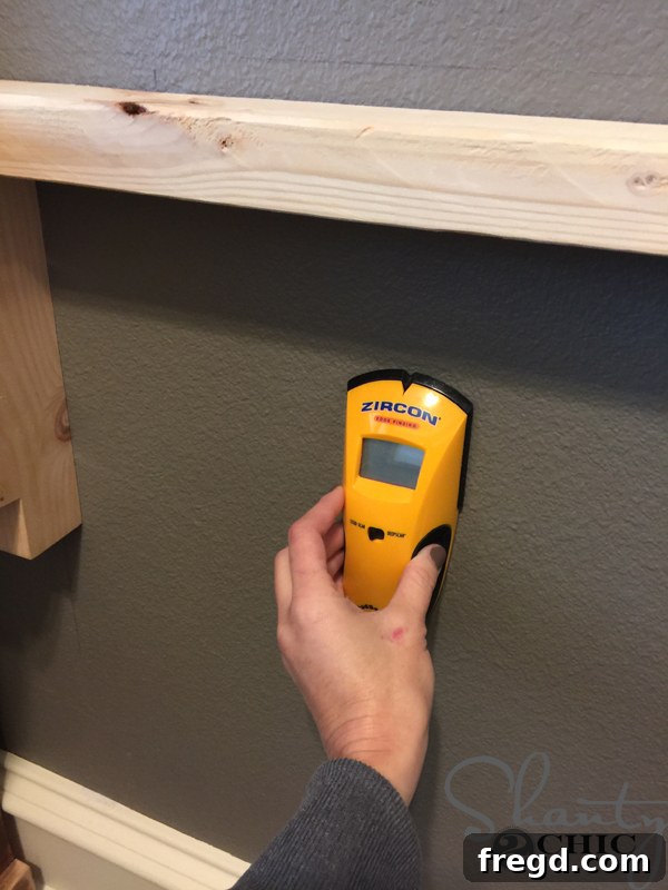 Using a stud finder to locate wall studs behind the cleat