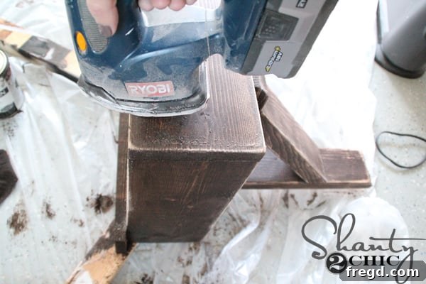 Distressing the stained desk surface with a sander
