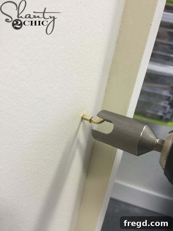 Attaching gold cup hooks for jewelry storage inside vanity doors