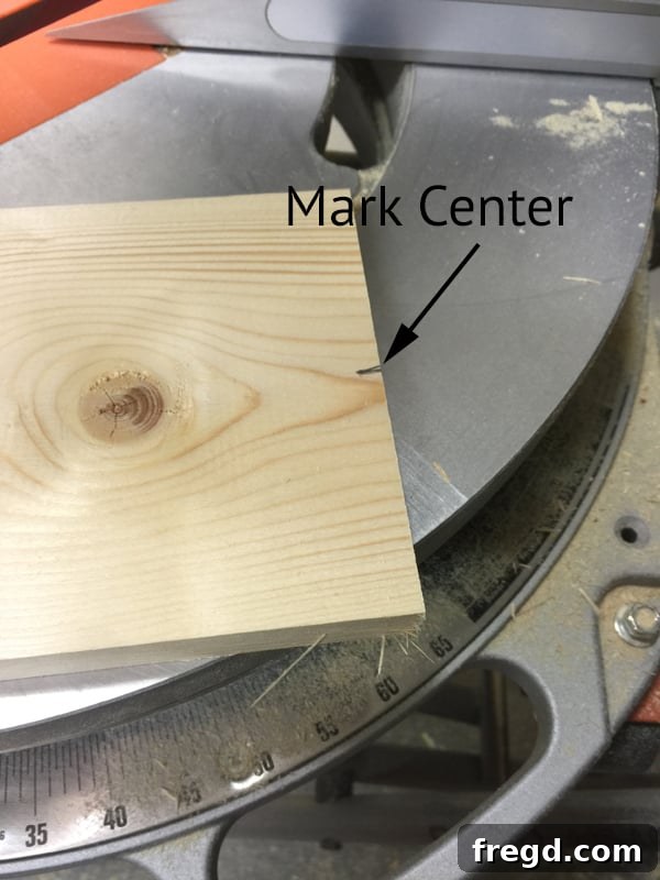 Build Your Own Rolling Storage Ottoman Coffee Table 24 A carpenter's pencil marking the center point on the end of a wooden plank, crucial for precise angle cuts in woodworking.