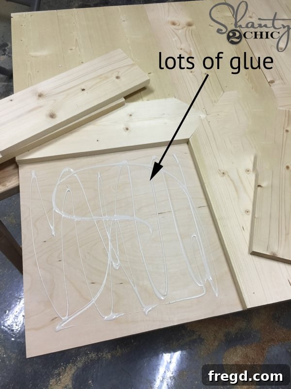 Build Your Own Rolling Storage Ottoman Coffee Table 28 Wood glue being generously applied to a section of the tabletop, prepared for the next set of wooden planks to form the pattern.
