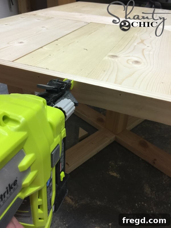 Build Your Own Rolling Storage Ottoman Coffee Table 31 A wooden trim piece being attached to the edge of a patterned tabletop using brad nails and wood glue, creating a finished look.