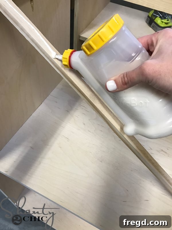 Craft Your Own Sliding Barn Door Nightstand 11 Applying wood glue to the back of a small trim piece for the shelf edge