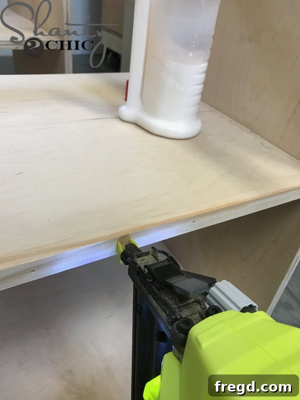 Craft Your Own Sliding Barn Door Nightstand 12 Attaching the trim piece to the shelf with a brad nailer