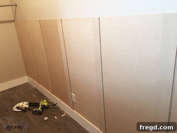 Ultimate Laundry Room Makeover 10 MDF panels being installed sequentially down the wall