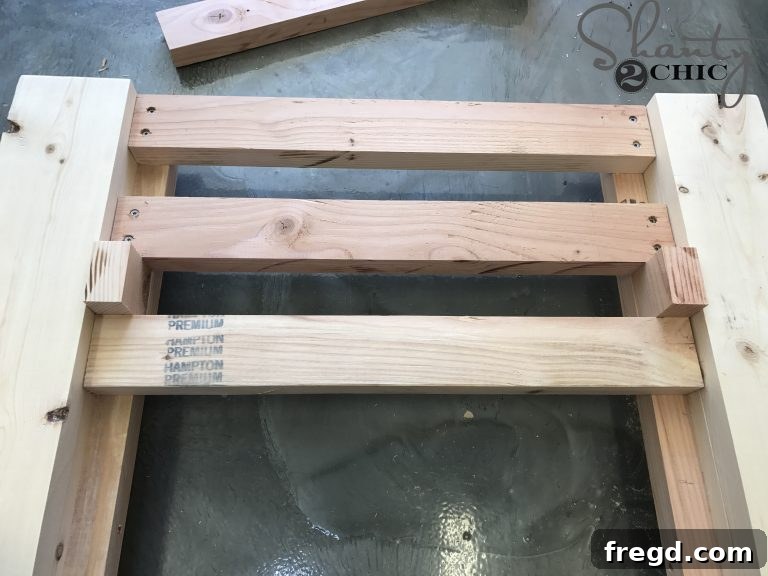 Assembling the bottom seat of the DIY lounge chair, showing slats being attached with screws and glue, using spacer blocks for even gaps.