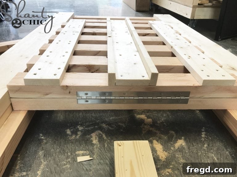 Attaching the piano hinge to the top slat of the seat and the bottom of the backrest, with the backrest upside down and flush for alignment.