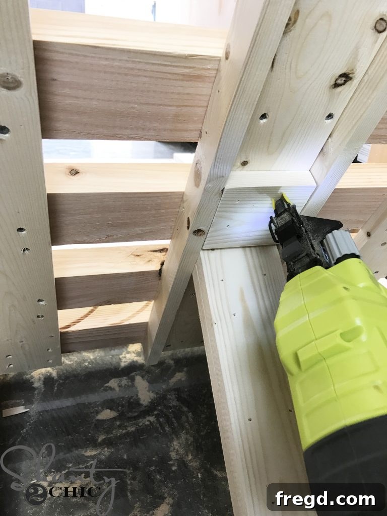 A close-up of stop blocks being attached with a nailer and wood glue to the inside of the arm guide for adjustable backrest positions.