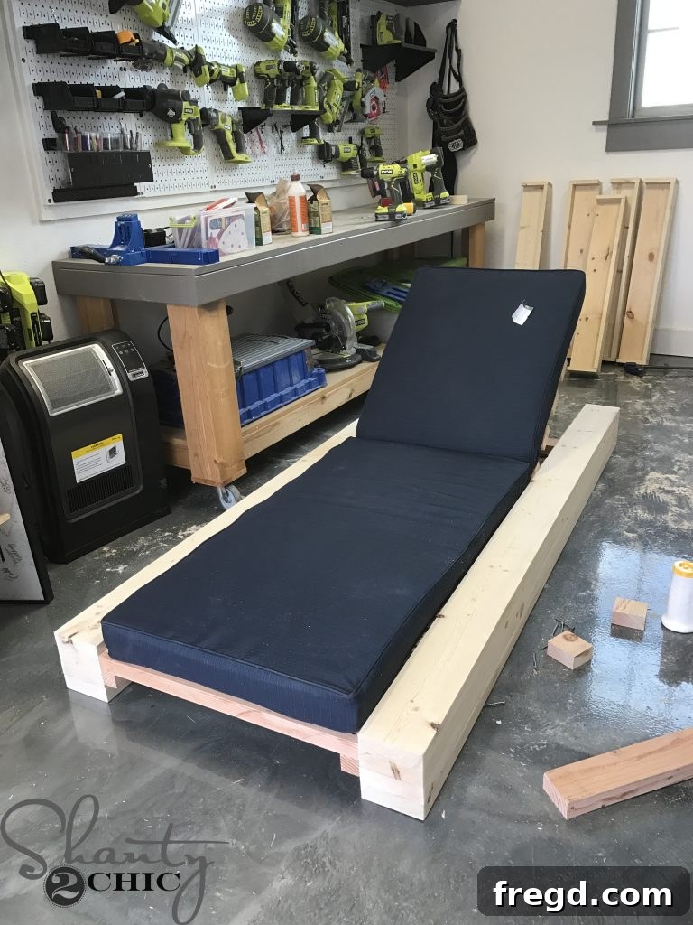 Testing the fit of an outdoor cushion on the newly built DIY lounge chair, confirming dimensions and comfort.