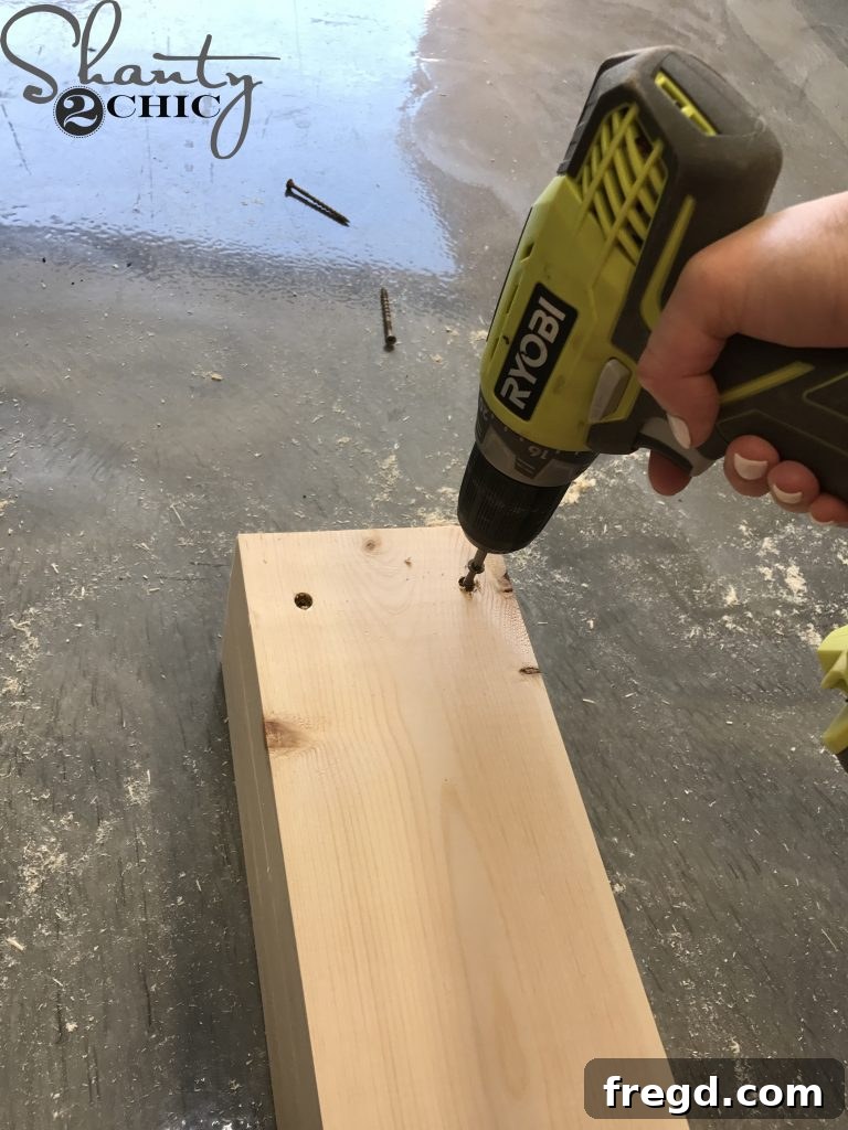 Securing two stacked 2x6 boards with deck screws, ensuring a strong and hidden attachment for the DIY outdoor lounge chair side frame.