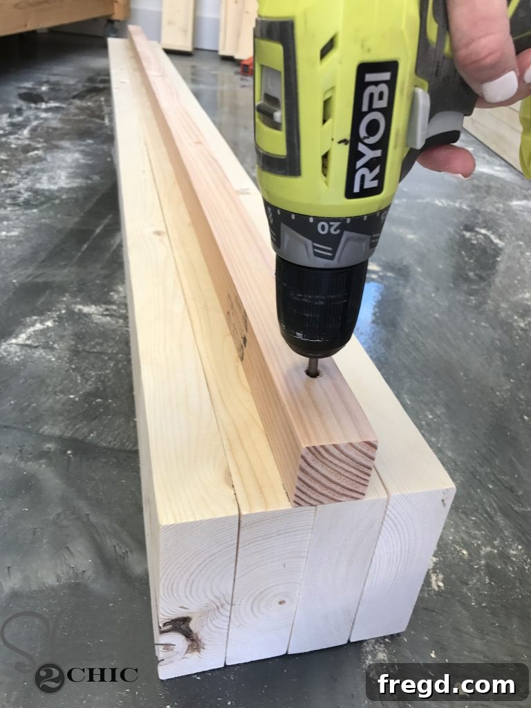 Applying wood glue to a 2x2 cleat using a Glue Bot, preparing it for attachment to the lounge chair side panel for added support.