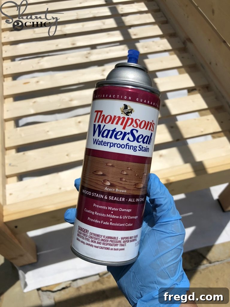 Applying an outdoor stain and sealant spray to the finished day bed frame