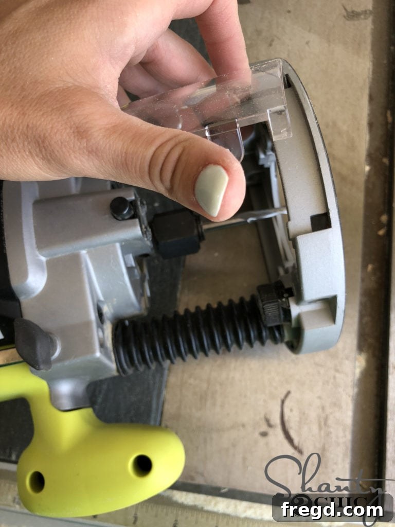 The process of carefully removing the clear plastic guard from the base of the plunge router