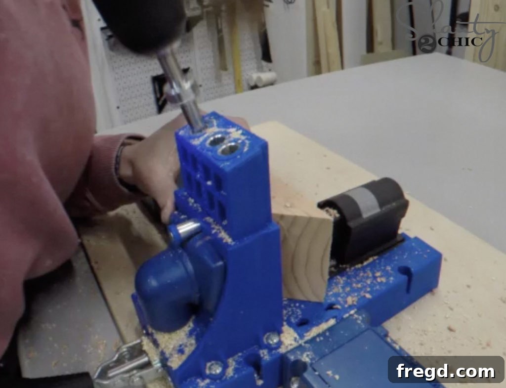 A Kreg Jig being used to drill precise 1 1/2-inch pocket holes along one edge of a wooden apron piece, preparing it for assembly.