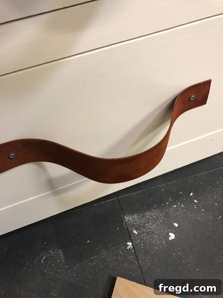 Close up view of the leather pull being secured to the drawer