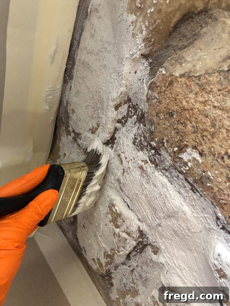 Brushing mortar onto stone fireplace for German Schmear