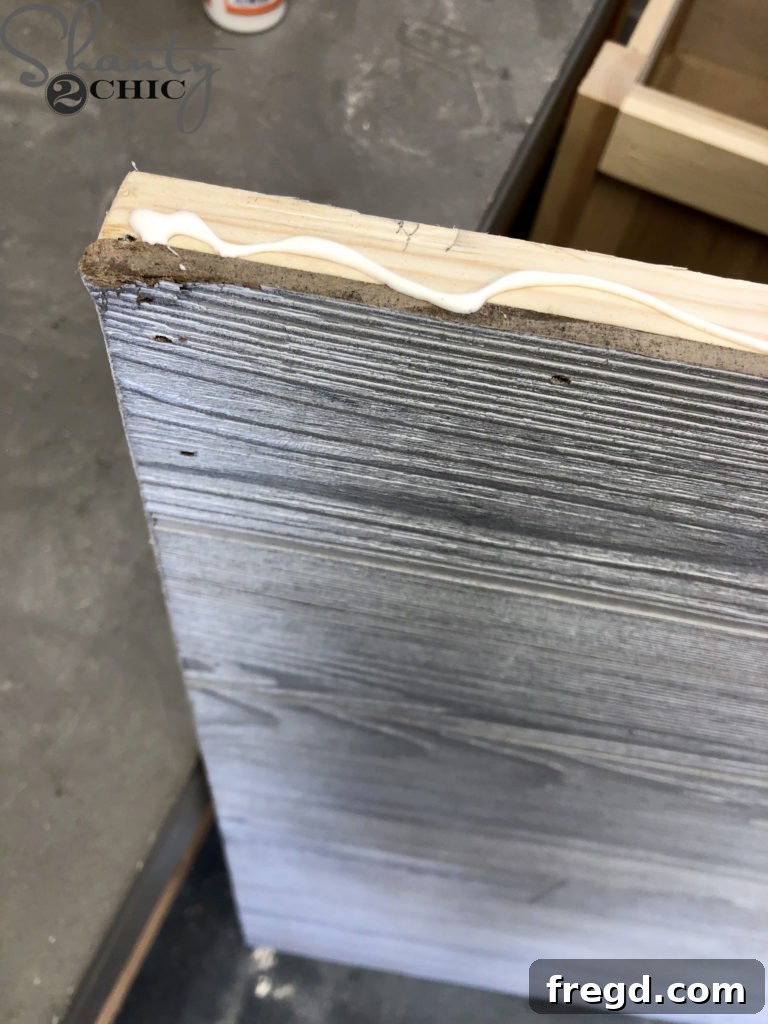 Applying wood glue to the edges of the barn door frame for trim attachment