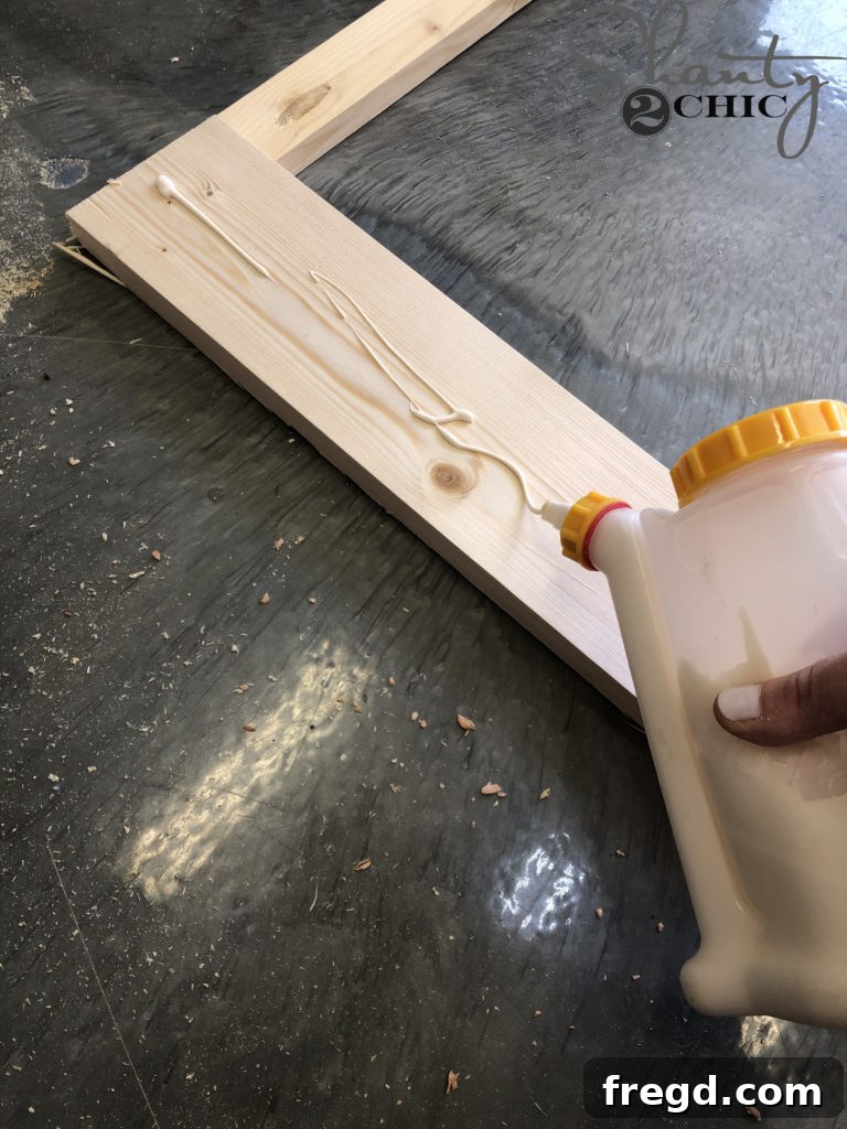 Applying wood glue evenly to the barn door frame before attaching the MDF panel
