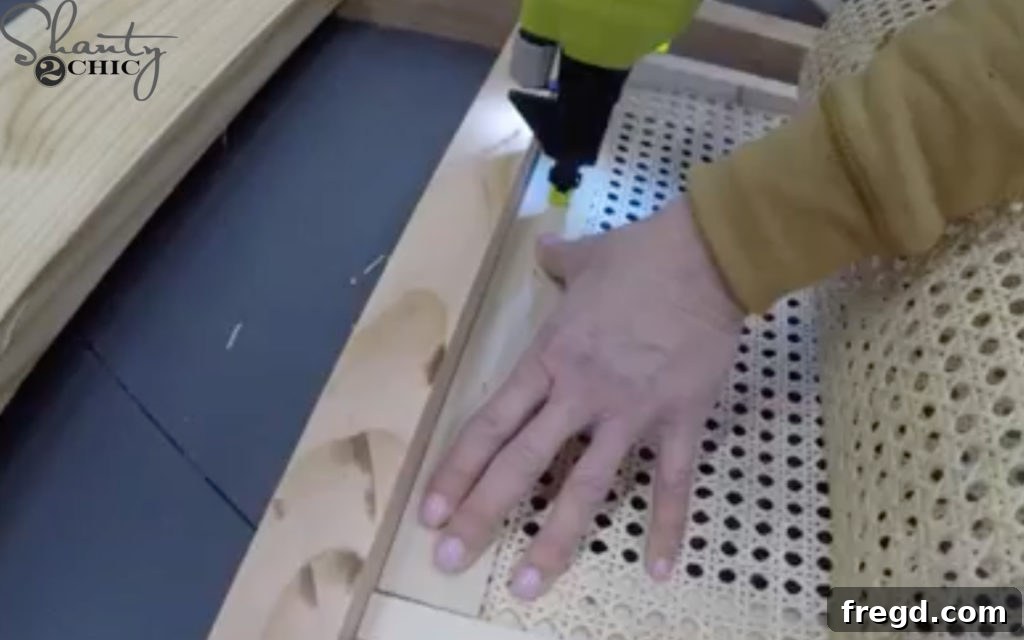 Attaching cane webbing with staples and trim pieces.