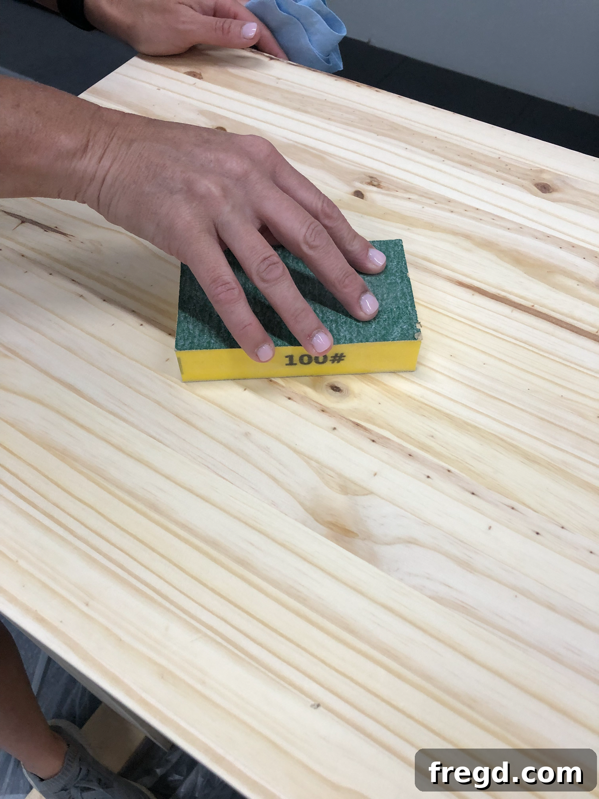 Hand sanding the console table with a coarse grit sponge