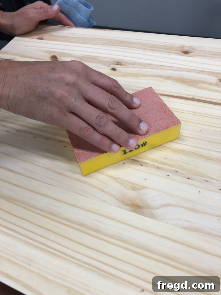 Applying medium grit sanding sponge to furniture