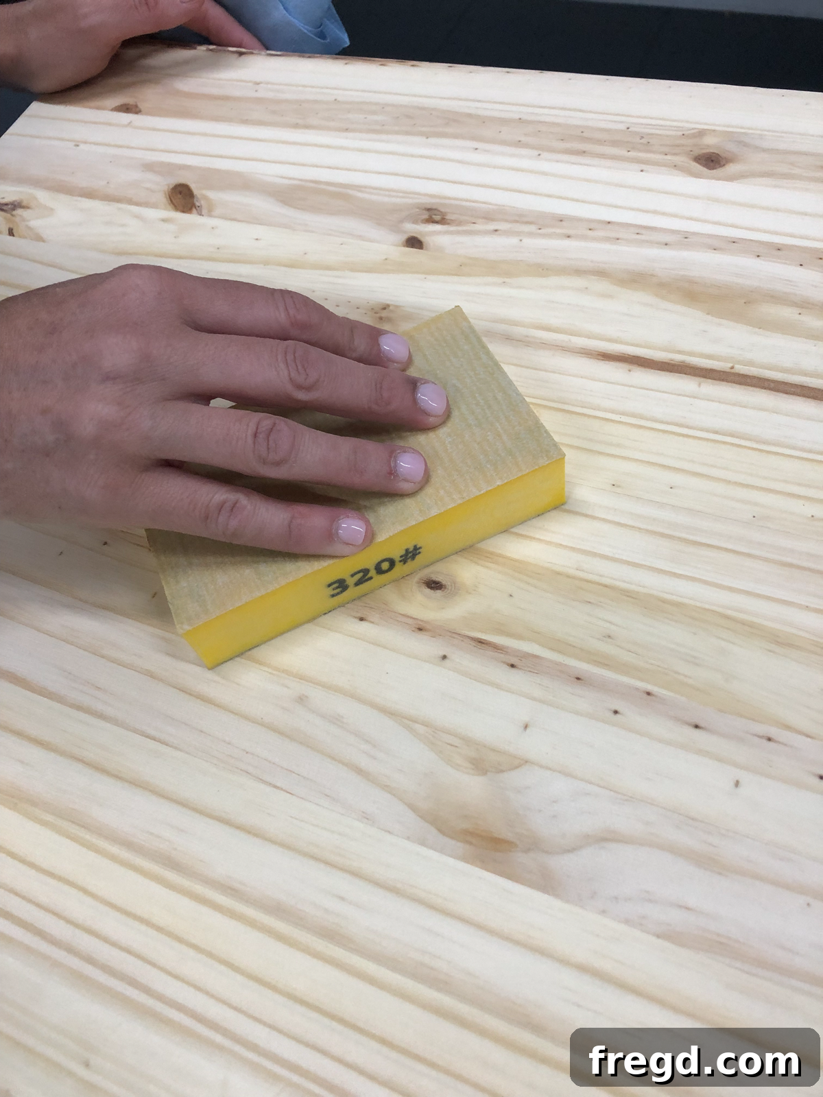Finishing sanding with a fine grit sponge on the console table
