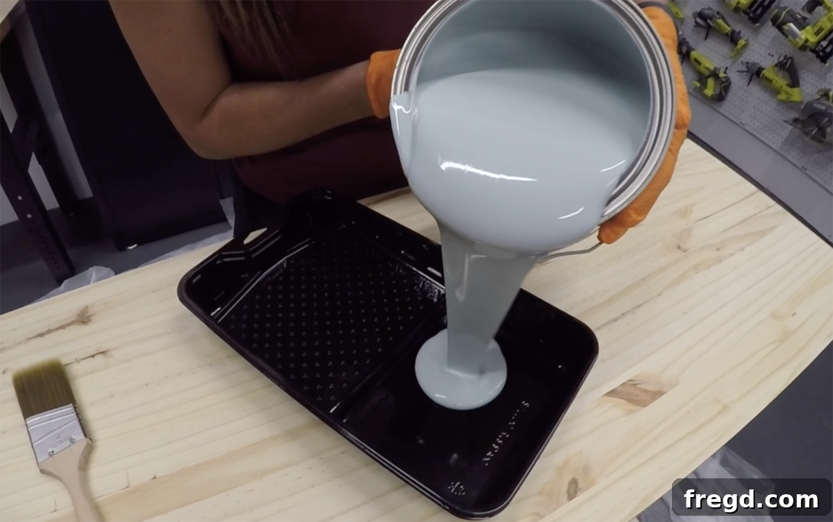 Pouring blue paint into a plastic paint tray