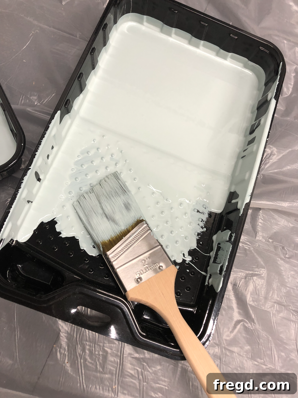 Paint brush dipping into a plastic paint tray
