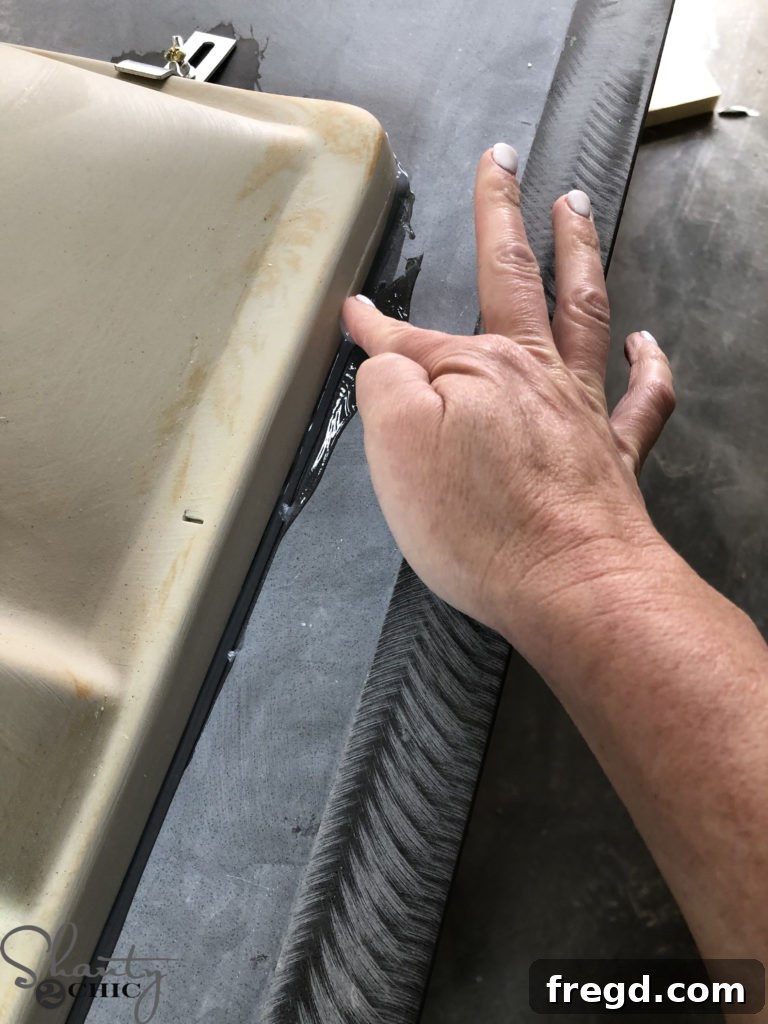 DIY Rustic Double Sink Bathroom Vanity with Barn Door Storage 43 Applying silicone to the undermount sinks for a smooth finish