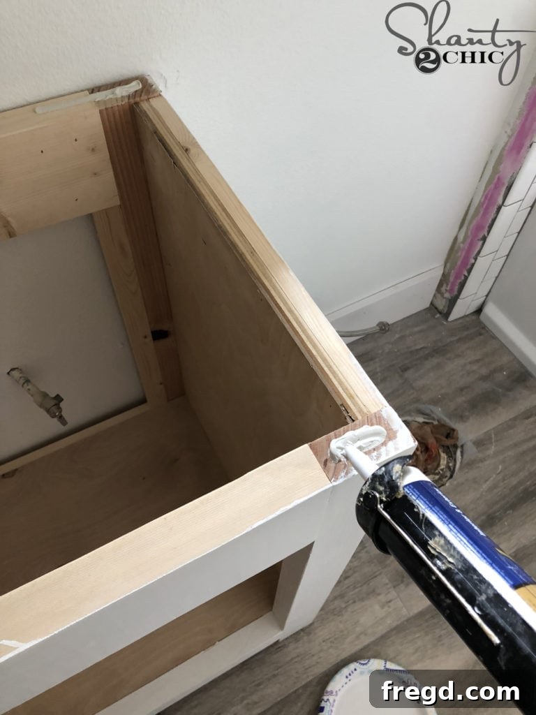 DIY Rustic Double Sink Bathroom Vanity with Barn Door Storage 50 Applying adhesive to attach the countertop to the vanity
