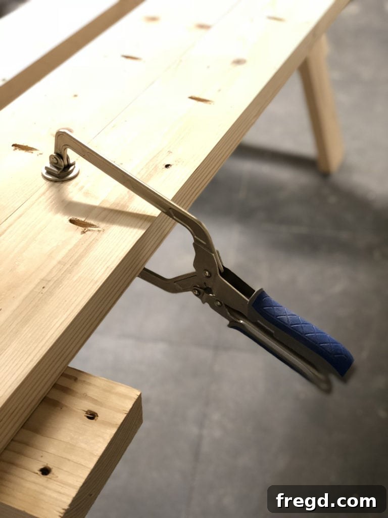 Sawhorse Chic: A DIY Modern Farmhouse Dining Table 3 Woodworker using a Kreg Face Clamp to align and flatten boards during tabletop construction