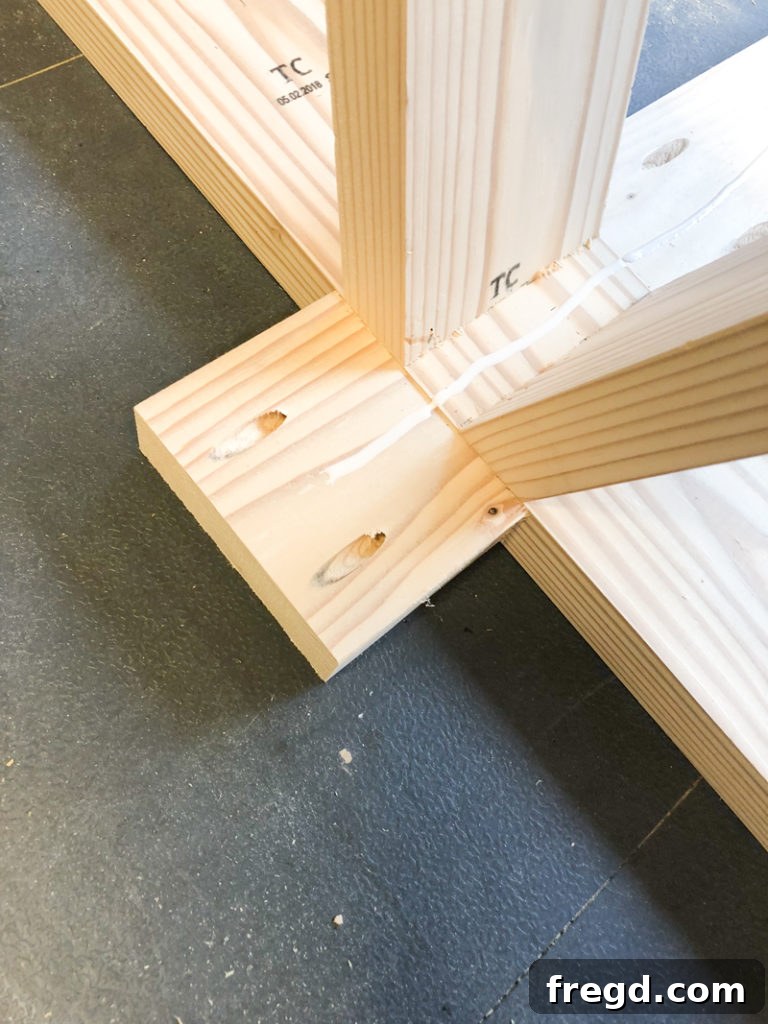 Sawhorse Chic: A DIY Modern Farmhouse Dining Table 25 Woodworker using a drill to attach the long runner to the table base