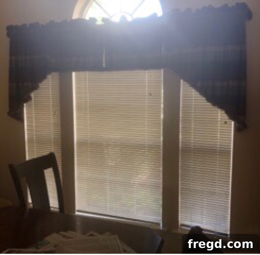 Before photo of an old dining room with a prominent, dated half-circle window.