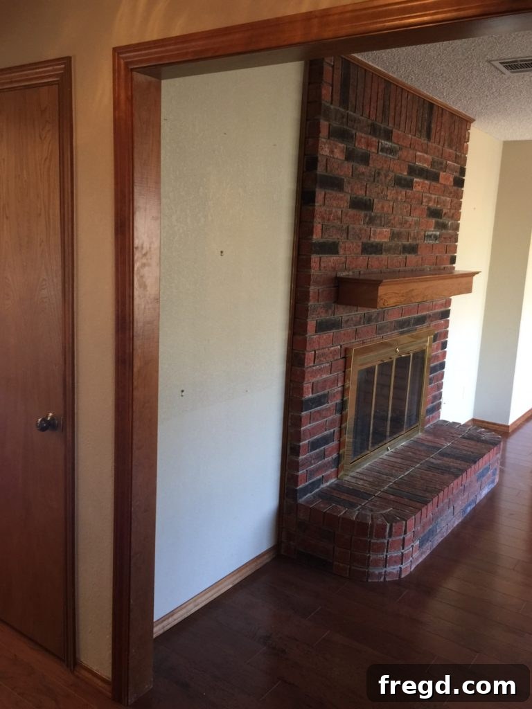 Before photo of the Davis home's double fireplace, obscured by dated cabinets on both sides.