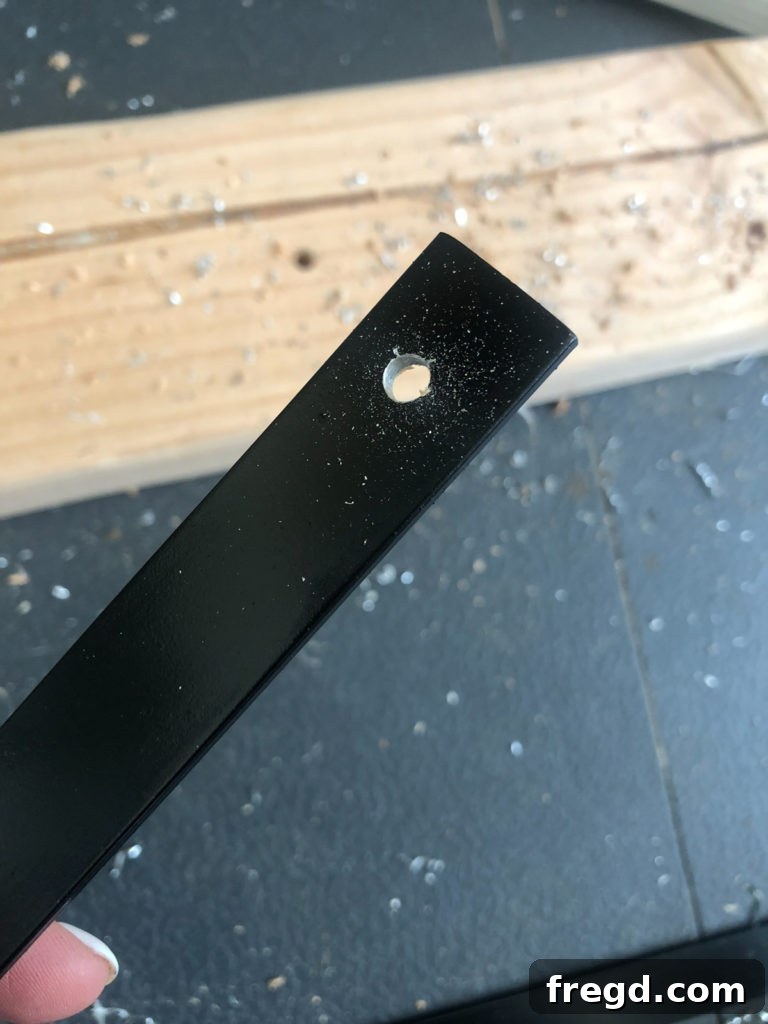 Close-up of multiple black-painted aluminum flat bars with pre-drilled holes at each end