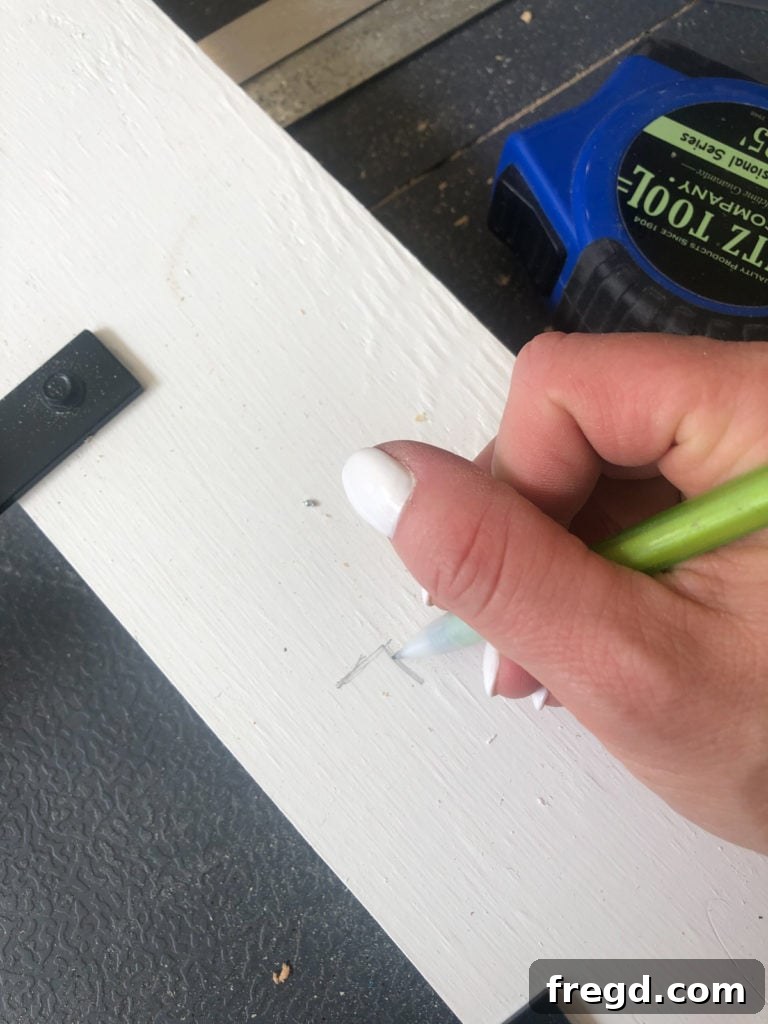 Marking out lines on the wooden side frame to guide the even spacing of the metal bars