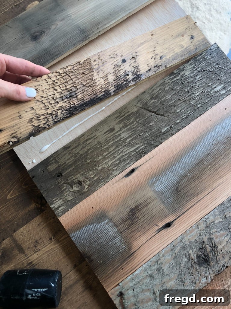 Attaching rustic barn wood planks to a plywood base to create the custom barn door for the dog crate