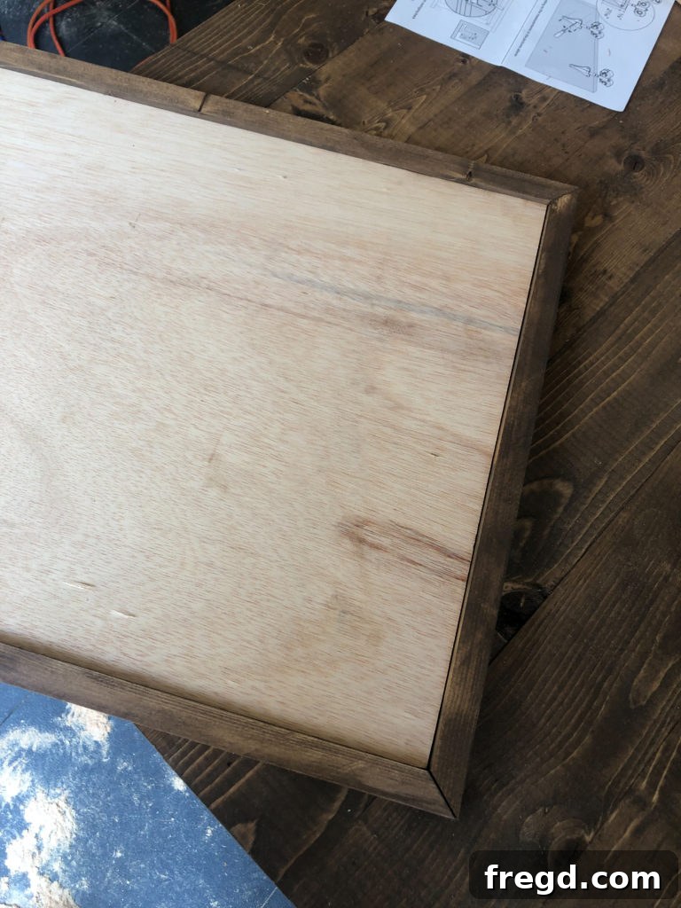Attaching mitered 1x2 trim boards to the perimeter of the barn door with wood glue and brad nails
