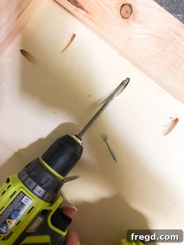 Attaching the plywood base to the wooden frame using wood glue and pocket hole screws
