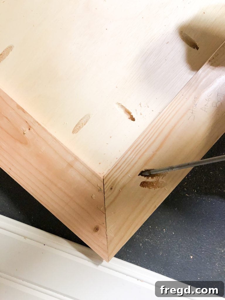 Securing the mitered corners of the base frame with 2-inch pocket hole screws for a strong joint