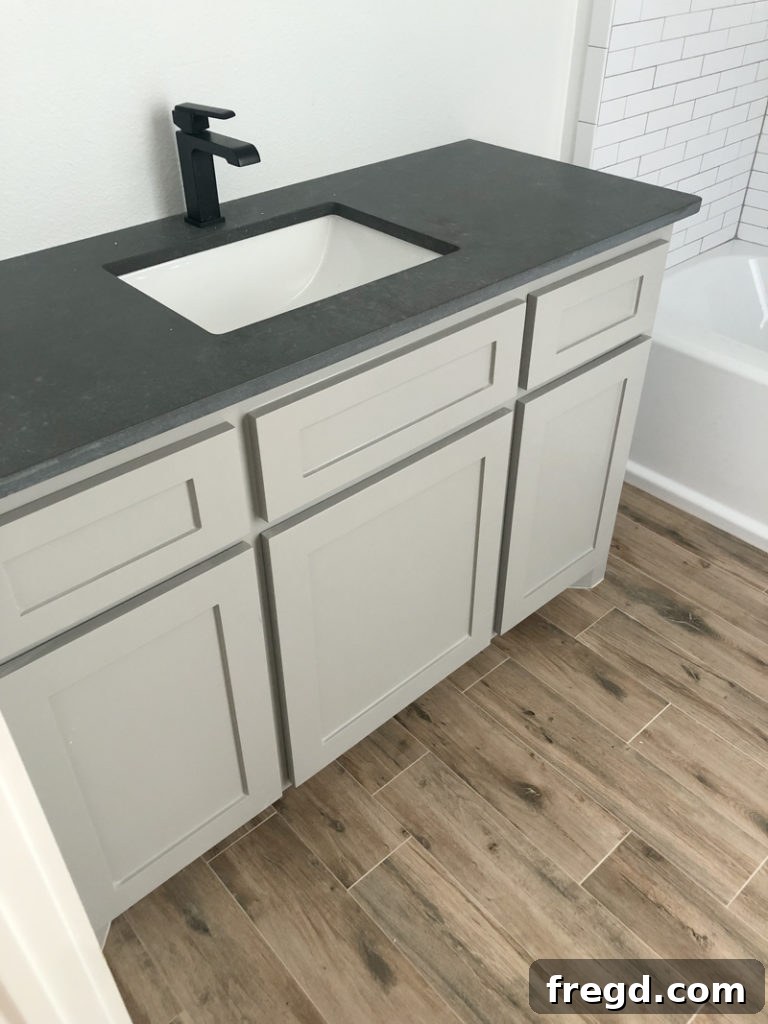 Paint Colors That Sell Your Flip House Fast 9 Bathroom with Sherwin-Williams Dorian Gray cabinets, faux wood tile, and dark countertops