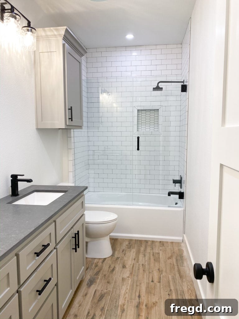 Finished upstairs bathroom shower featuring picket mosaic tile in a decorative niche and subway tiles.