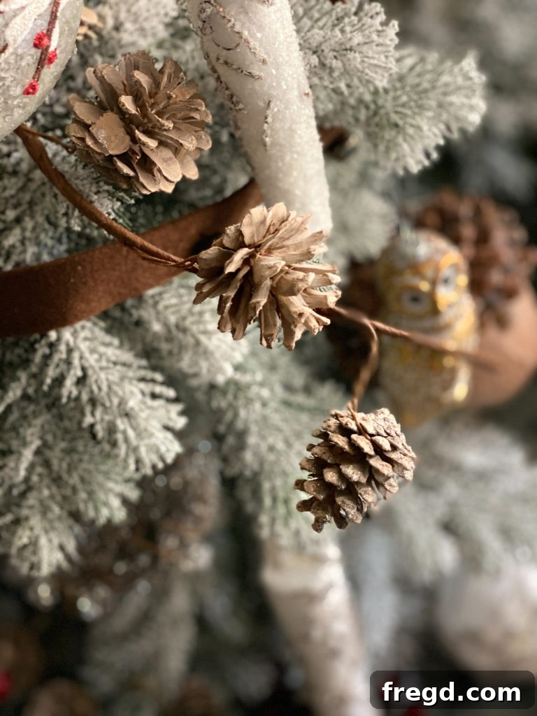 Detailed view of frosted pinecone and vibrant red berry picks nestled within the Christmas tree branches.