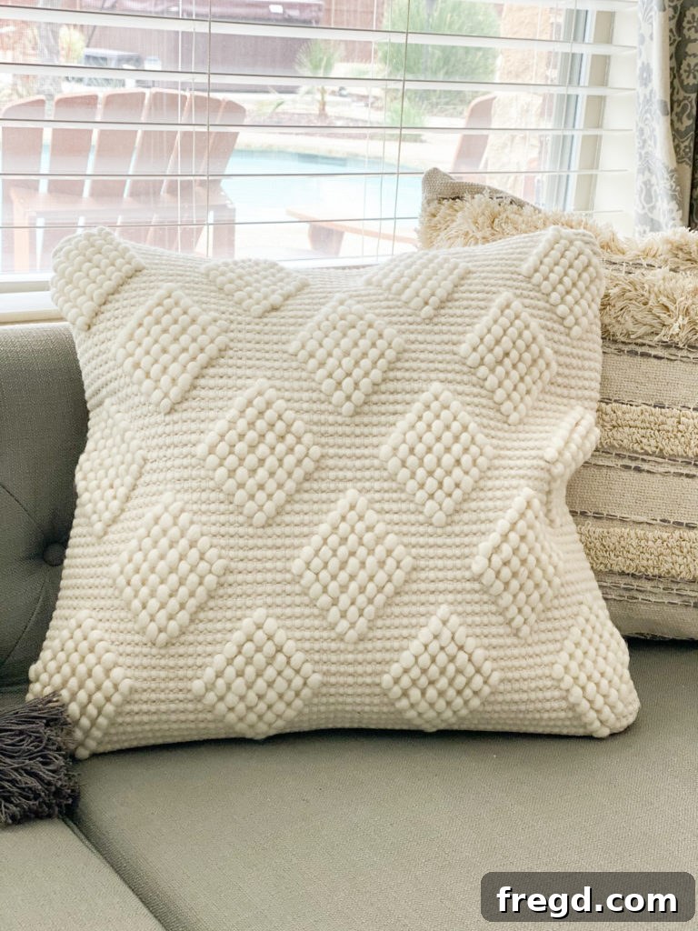 Luxurious cream throw pillow featuring a subtle, contemporary pattern woven into its soft, inviting texture.