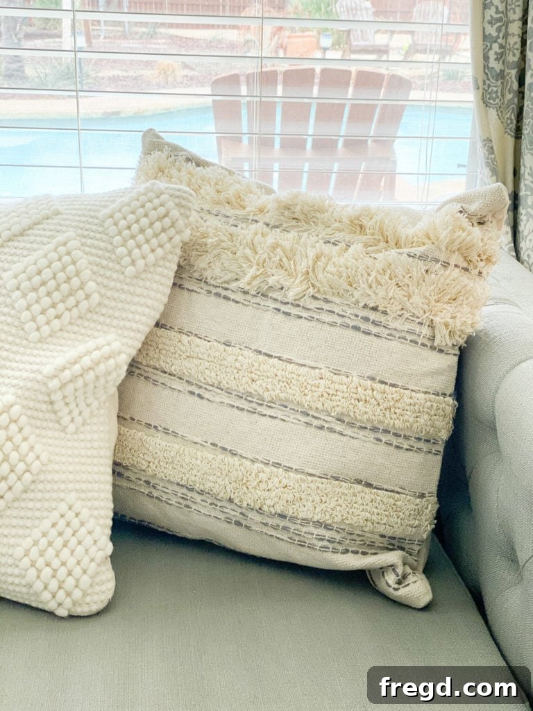 Close-up of a fringe pillow showcasing neutral gray and cream tones with a distinctive, textural weave.