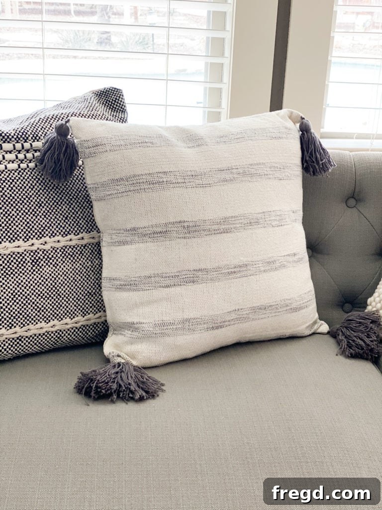 Close-up of a soft, white throw pillow adorned with elegant, decorative tassels, adding a playful touch.