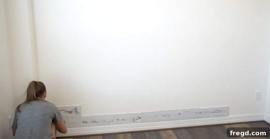 Quick and Easy Wood Plank Wall Upgrade 2 Beginning the installation of wood planks on the accent wall, showing the first few boards being secured